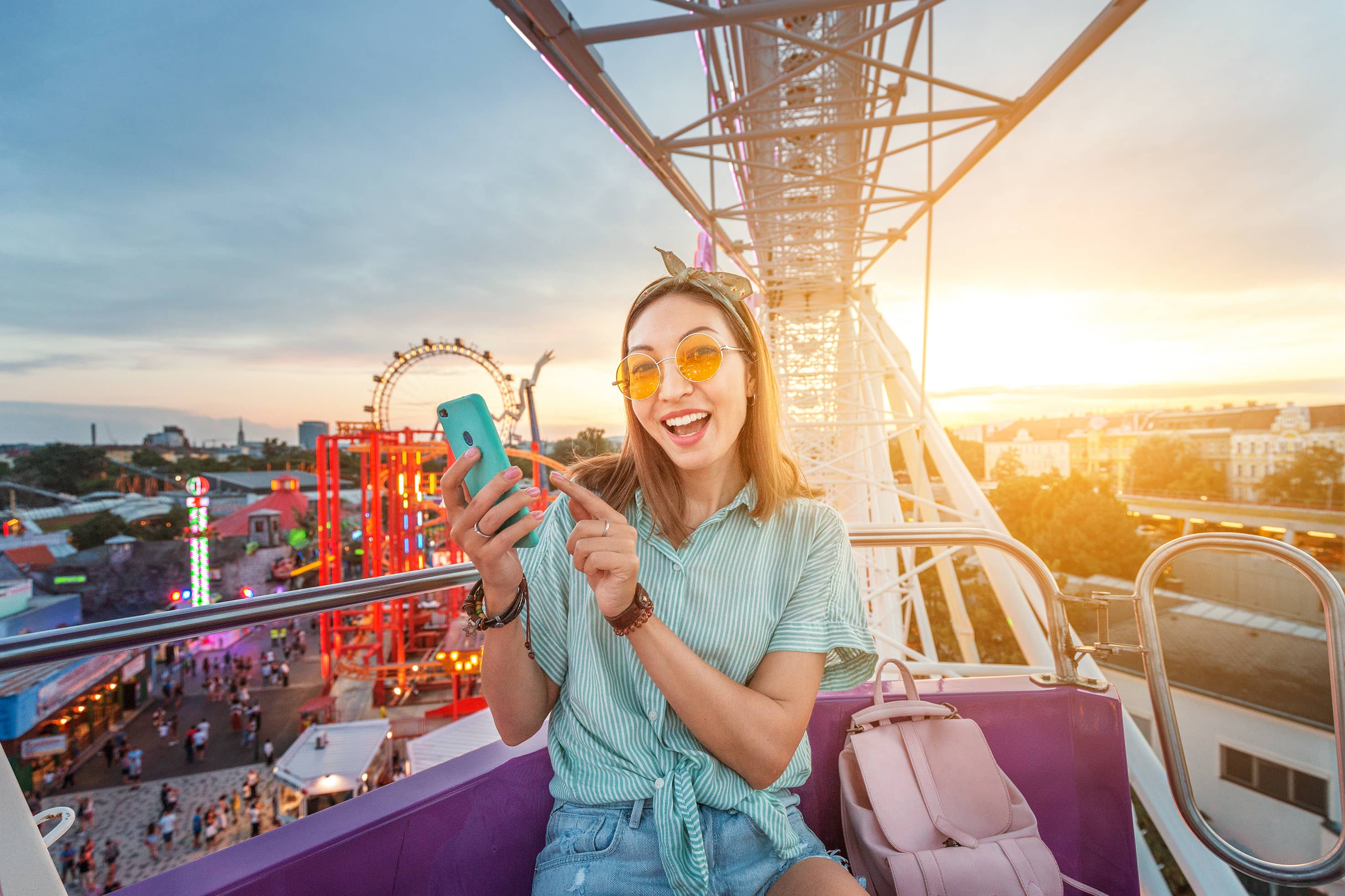 girl-using-phone-at-theme-park-ferris-wheel